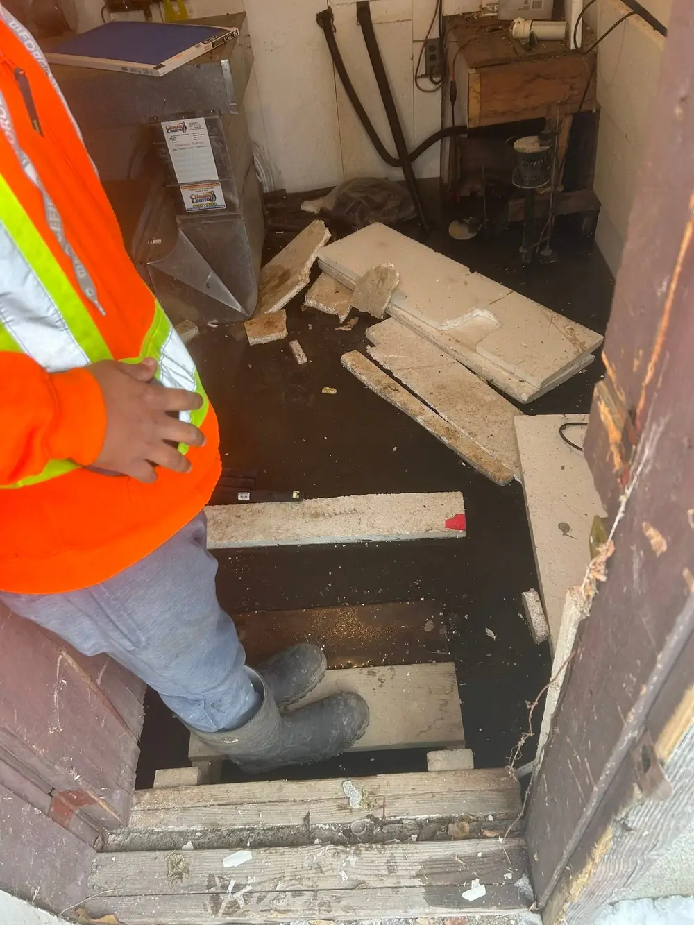 LKC Foundations crew member surveying a wet, cluttered basement before starting foundation work