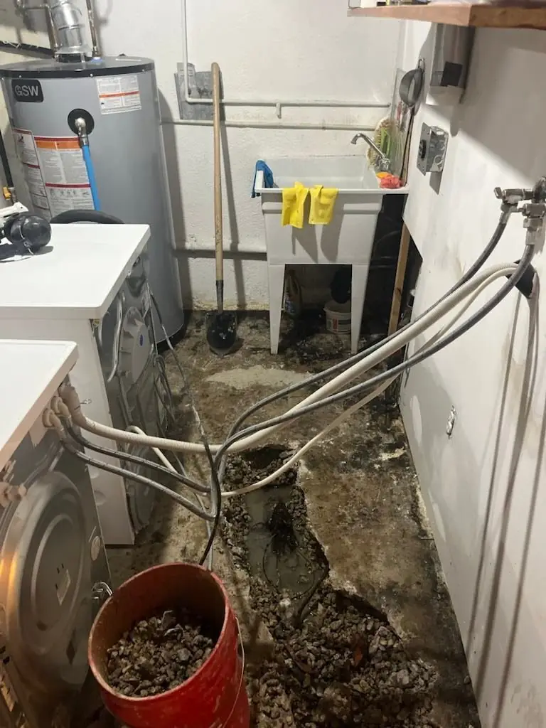 Basement utility room with concrete floor opened around a failing drain line for interior remediation